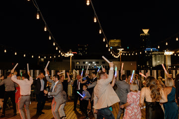 Wedding guests dancing under string lights on a rooftop venue at night with the Oklahoma City skyline in the background