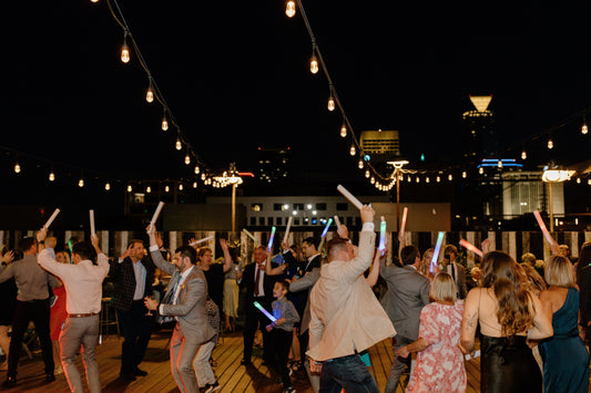 Wedding guests dancing under string lights on a rooftop venue at night with the Oklahoma City skyline in the background